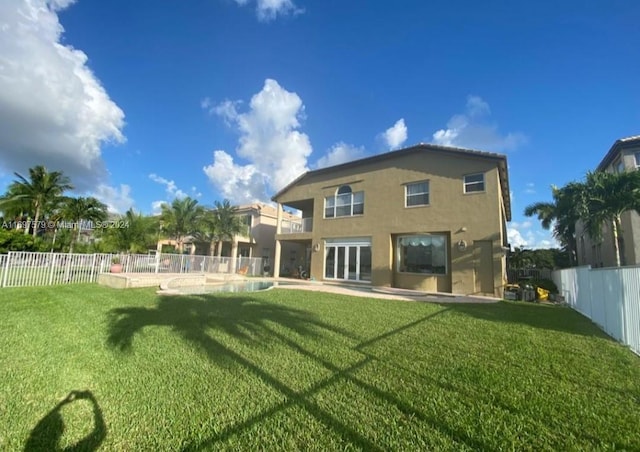 rear view of property with a yard and a fenced in pool