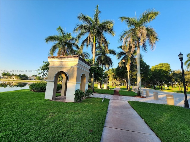 surrounding community with a water view and a yard