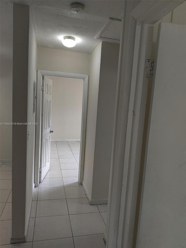 hallway with light tile patterned floors and a textured ceiling