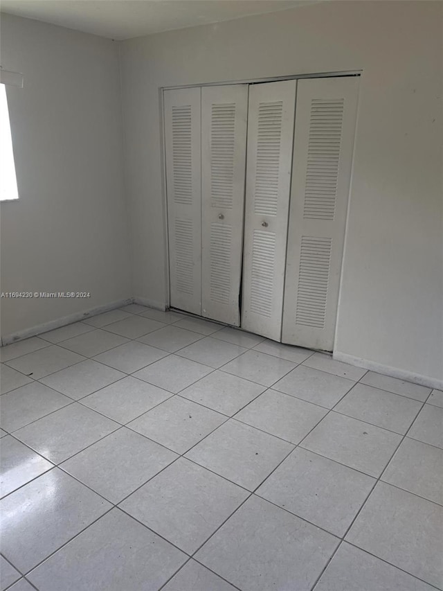 unfurnished bedroom featuring light tile patterned floors and a closet