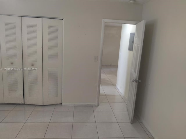 unfurnished bedroom with light tile patterned floors, electric panel, and a closet