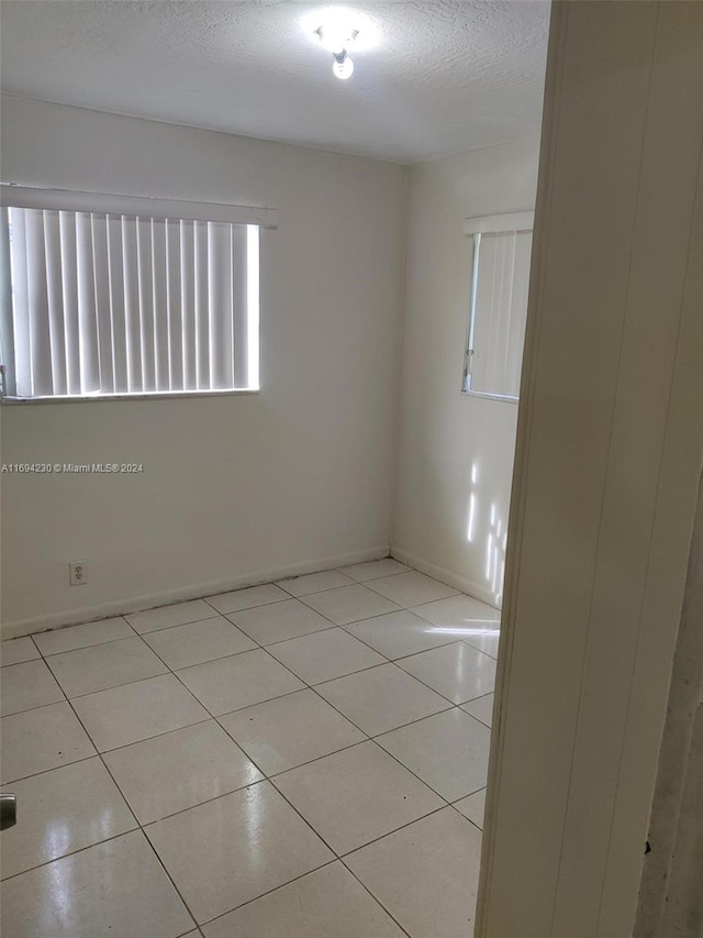 tiled spare room with a textured ceiling