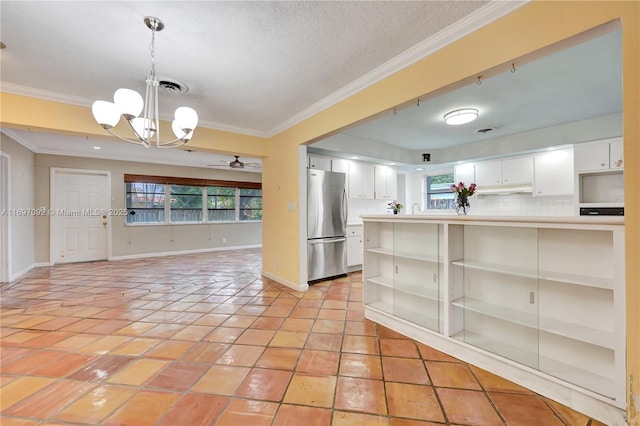 kitchen with white cabinetry, hanging light fixtures, backsplash, and stainless steel fridge