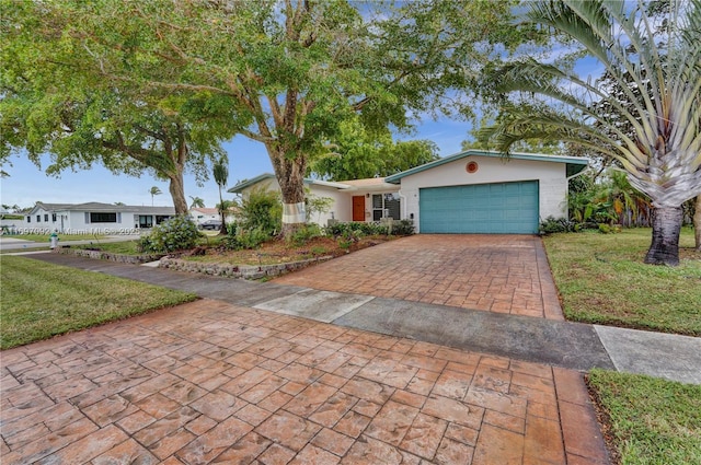 ranch-style house featuring a garage and a front lawn