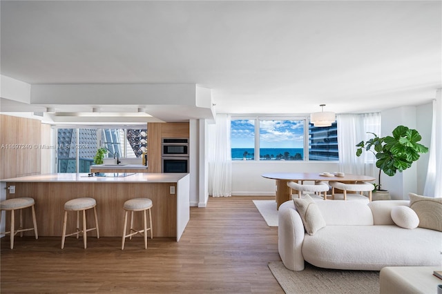 kitchen featuring kitchen peninsula, a kitchen bar, stainless steel double oven, sink, and wood-type flooring