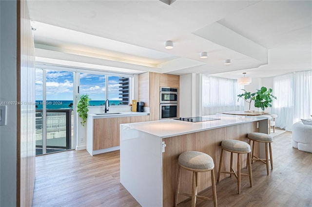 kitchen featuring double oven, sink, a kitchen island, and light hardwood / wood-style floors