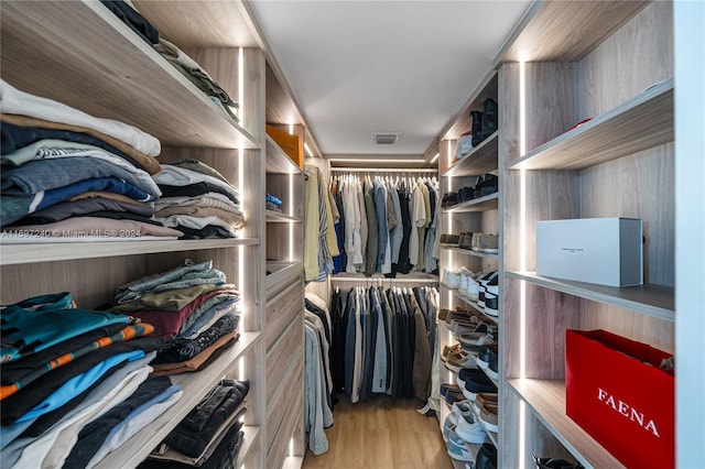 walk in closet with light hardwood / wood-style flooring