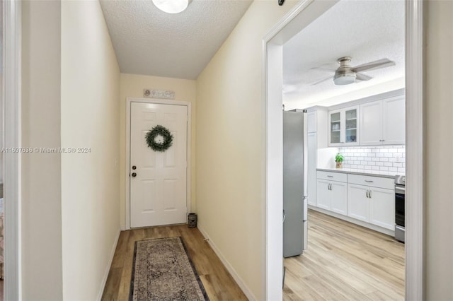 entryway featuring ceiling fan, light hardwood / wood-style floors, and a textured ceiling