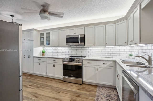 kitchen with white cabinetry, sink, light wood-type flooring, and appliances with stainless steel finishes