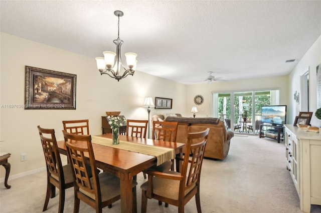 dining space featuring ceiling fan with notable chandelier, light colored carpet, and a textured ceiling