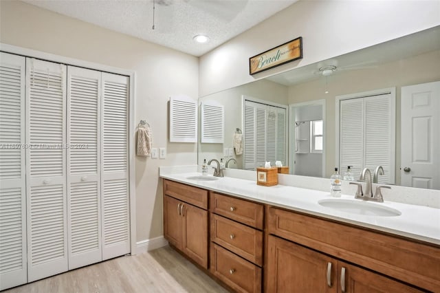 bathroom featuring hardwood / wood-style flooring, ceiling fan, a textured ceiling, and vanity