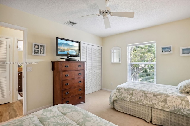 bedroom with light carpet, a textured ceiling, a closet, and ceiling fan