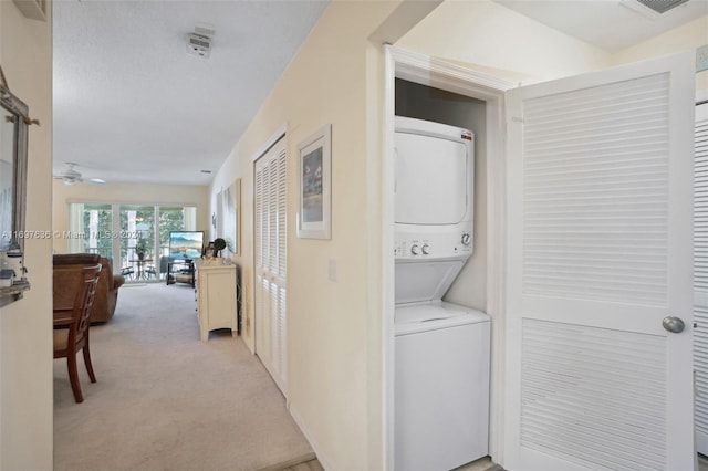 hallway featuring light carpet, vaulted ceiling, and stacked washer and clothes dryer