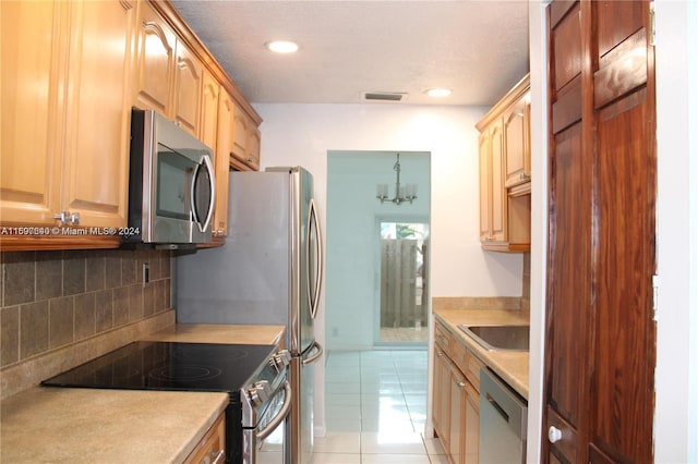 kitchen with an inviting chandelier, sink, decorative backsplash, light tile patterned floors, and appliances with stainless steel finishes