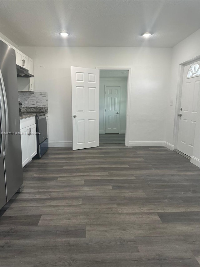 kitchen with black electric range oven, decorative backsplash, dark hardwood / wood-style flooring, white cabinetry, and stainless steel refrigerator