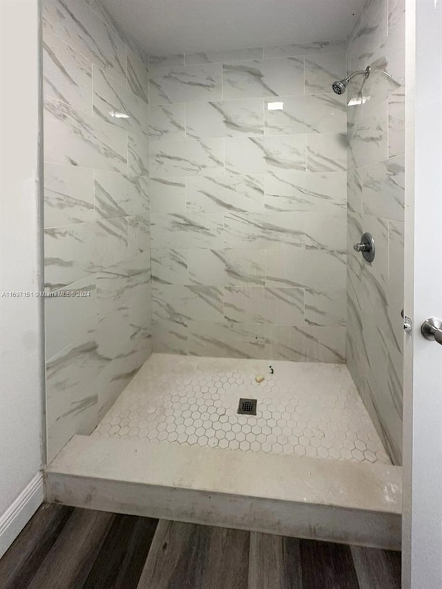 bathroom featuring hardwood / wood-style flooring and a tile shower