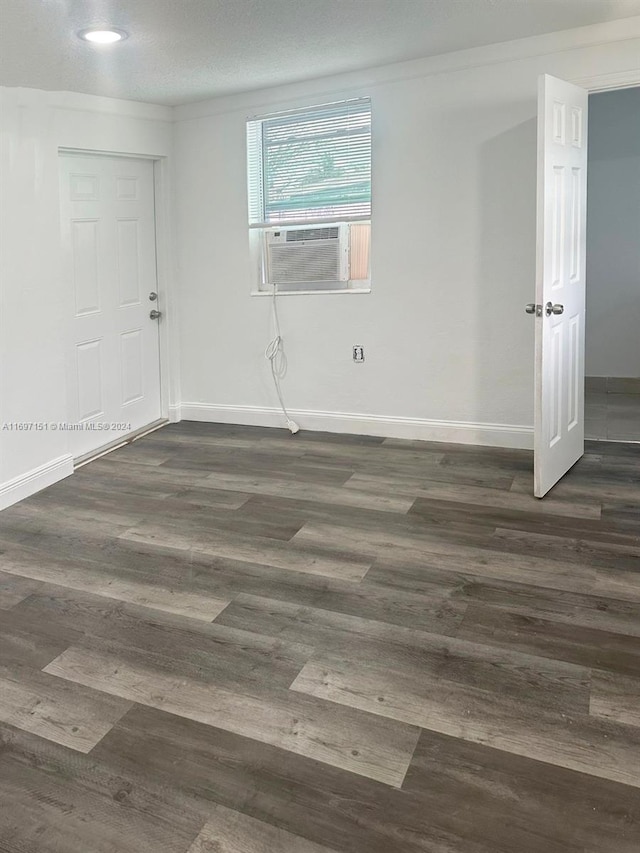 empty room featuring a textured ceiling, dark hardwood / wood-style floors, and cooling unit