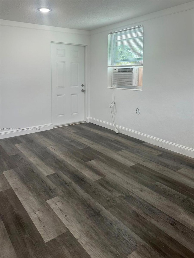 empty room with a textured ceiling, dark hardwood / wood-style flooring, and cooling unit