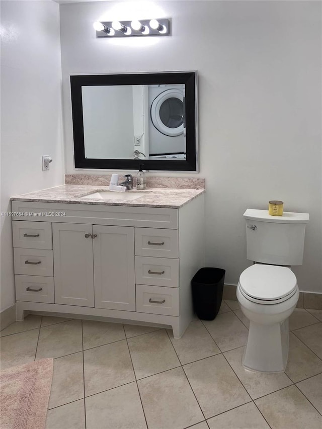 bathroom with tile patterned flooring, vanity, toilet, and stacked washing maching and dryer