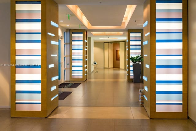 entryway with light tile patterned floors and a raised ceiling