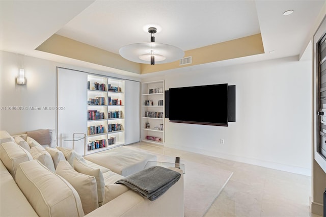 living room with built in shelves and a tray ceiling