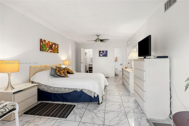 bedroom featuring ceiling fan, a textured ceiling, and connected bathroom