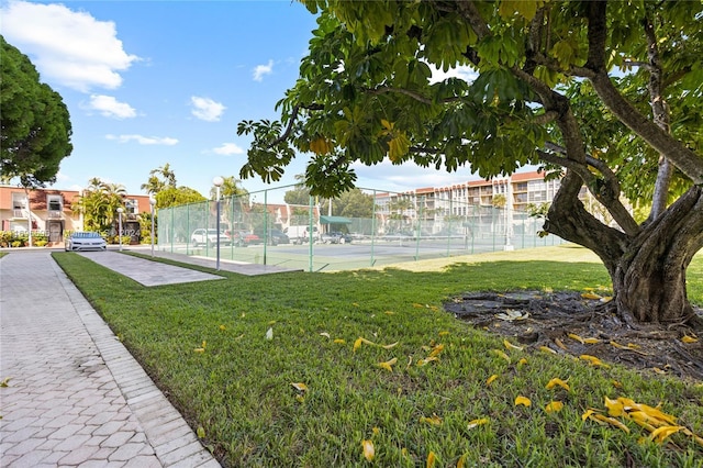 view of property's community with a yard and tennis court