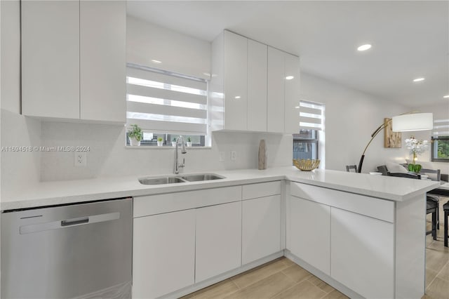 kitchen featuring dishwasher, white cabinetry, kitchen peninsula, and sink