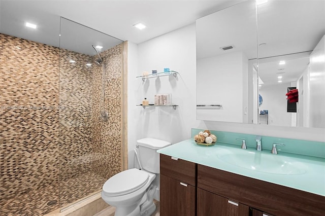 bathroom featuring vanity, toilet, and tiled shower