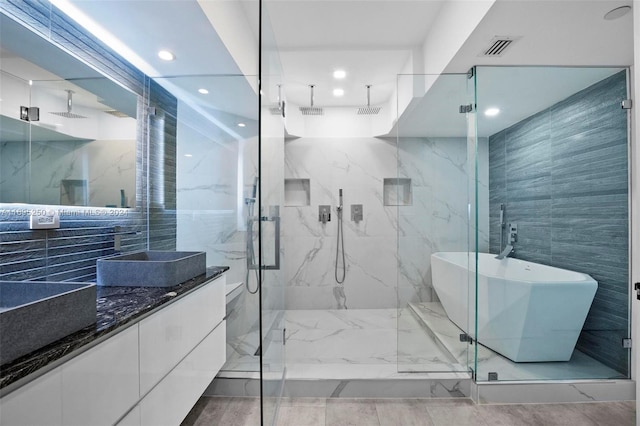 bathroom featuring plus walk in shower, vanity, and tile walls