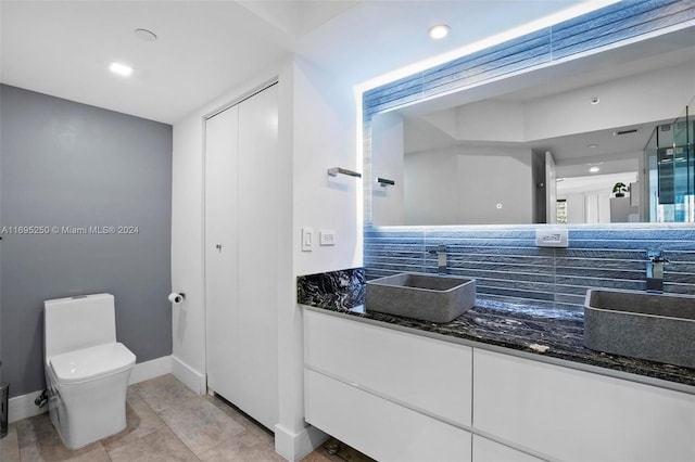 bathroom featuring vanity, backsplash, tile patterned floors, toilet, and a shower with shower door