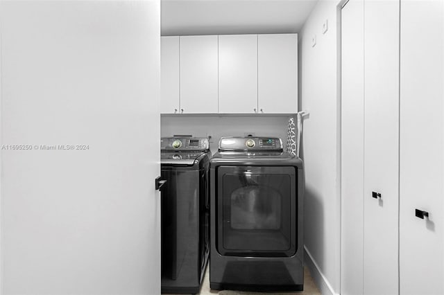 washroom with washing machine and clothes dryer and cabinets