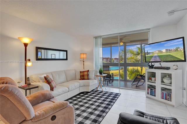 living room with ceiling fan, light tile patterned flooring, and a textured ceiling