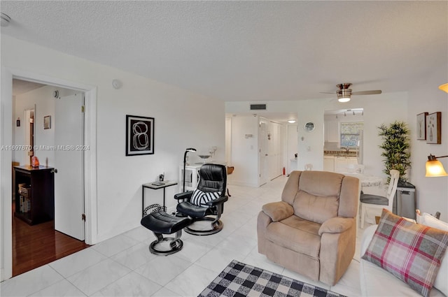 living room featuring ceiling fan, sink, a textured ceiling, and light hardwood / wood-style flooring