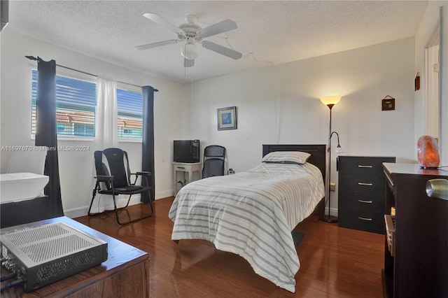 bedroom with a textured ceiling, ceiling fan, and dark hardwood / wood-style floors