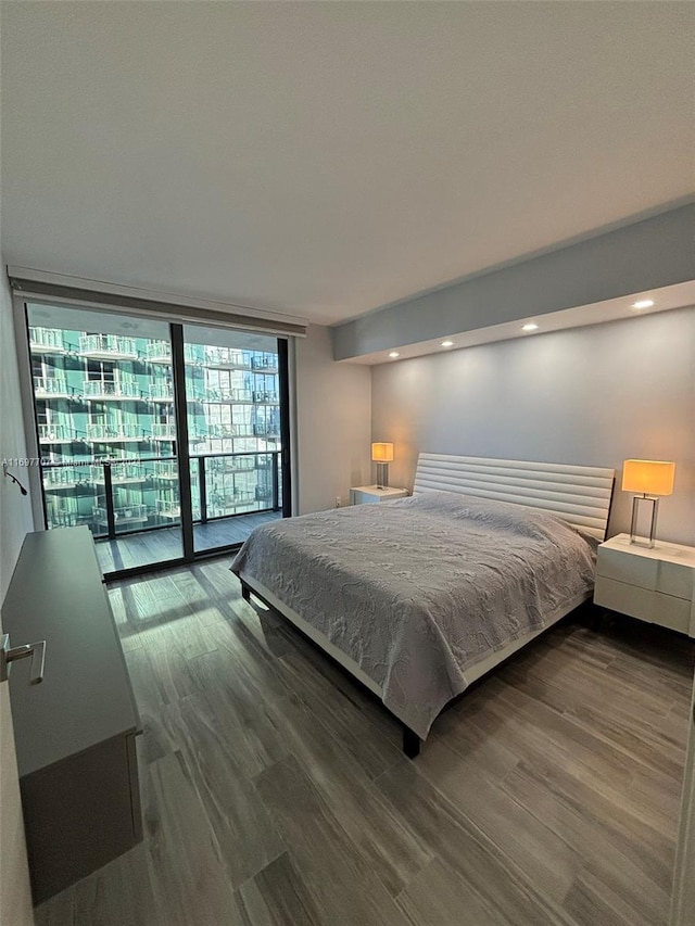 bedroom featuring dark hardwood / wood-style floors, expansive windows, and access to outside