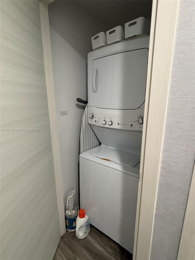 clothes washing area with hardwood / wood-style floors and stacked washing maching and dryer