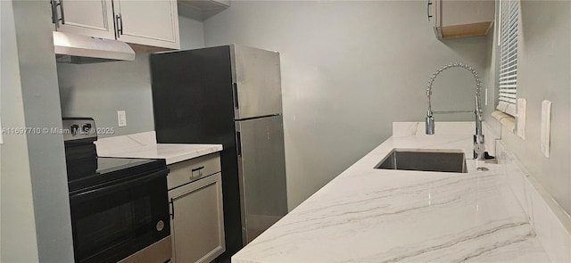 kitchen with under cabinet range hood, a sink, white cabinets, appliances with stainless steel finishes, and light stone countertops