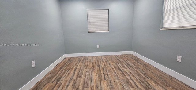 spare room featuring baseboards and wood finished floors