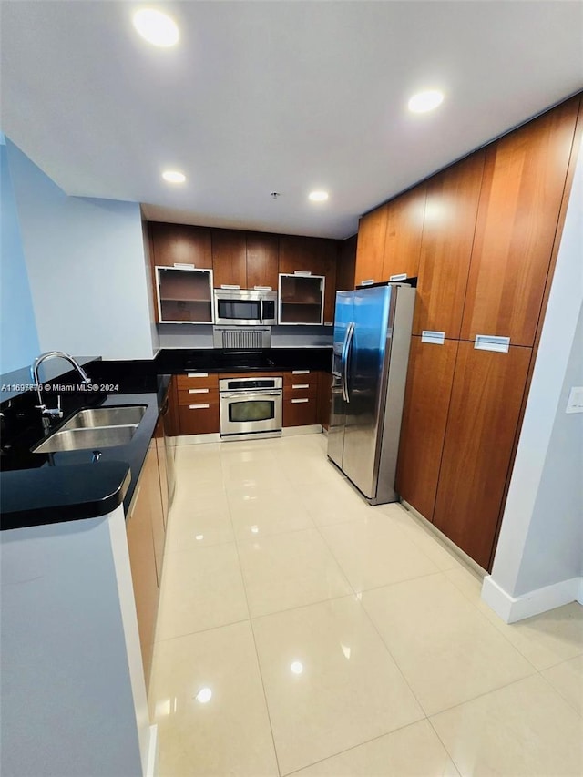 kitchen featuring kitchen peninsula, sink, light tile patterned floors, and appliances with stainless steel finishes