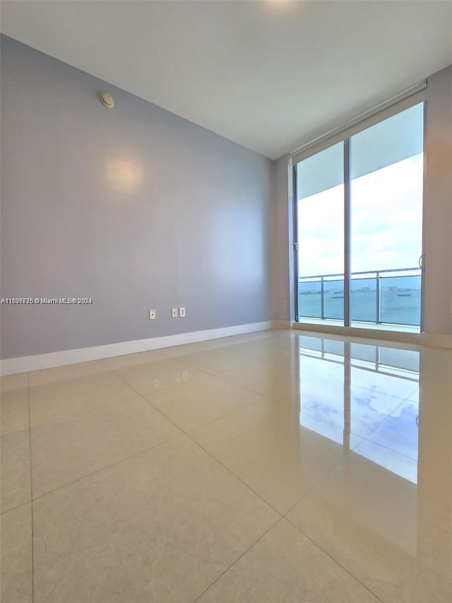 tiled spare room with a water view and a wall of windows