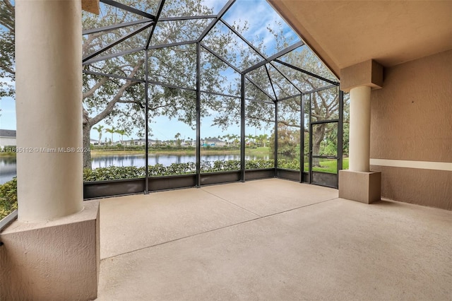 unfurnished sunroom with a healthy amount of sunlight, a water view, lofted ceiling, and a pool