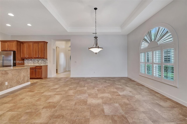 kitchen with pendant lighting, a tray ceiling, stainless steel refrigerator, and a wealth of natural light