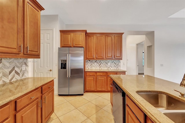 kitchen with sink, tasteful backsplash, light stone counters, light tile patterned flooring, and appliances with stainless steel finishes