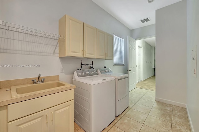 clothes washing area with cabinets, light tile patterned floors, sink, and washing machine and dryer