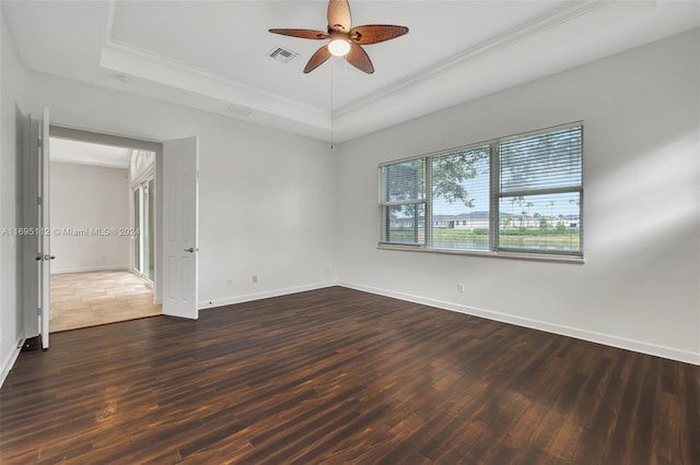 spare room featuring ceiling fan, crown molding, dark wood-type flooring, and a tray ceiling