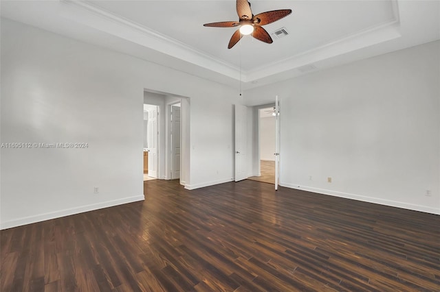 empty room featuring dark hardwood / wood-style floors, crown molding, ceiling fan, and a tray ceiling