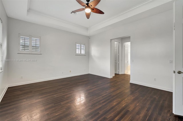 empty room featuring dark hardwood / wood-style floors, ceiling fan, and a tray ceiling