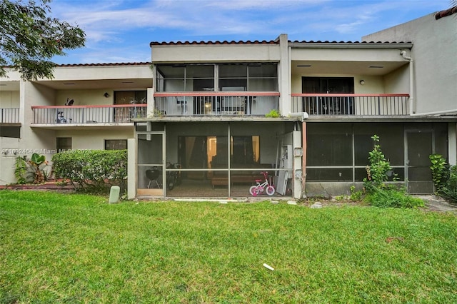 rear view of property featuring a sunroom and a lawn