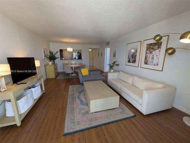 living room with a textured ceiling and dark hardwood / wood-style floors